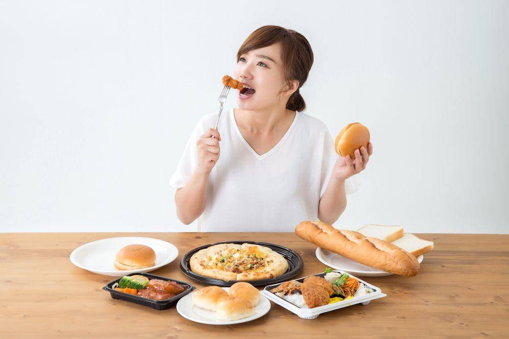 Seorang wanita sedang makan junk food (Shutterstock/buritora)