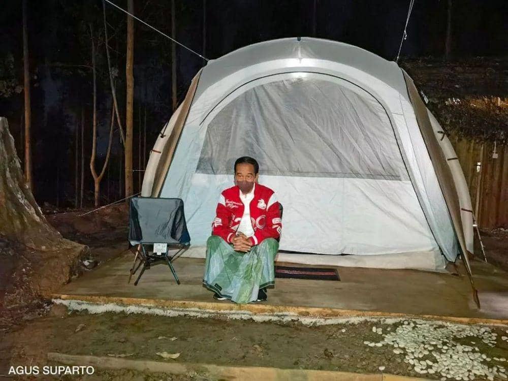 Jokowi duduk di depan tendanya pada malam hari. (Agus Suparto via Instagram.com/jokowi)