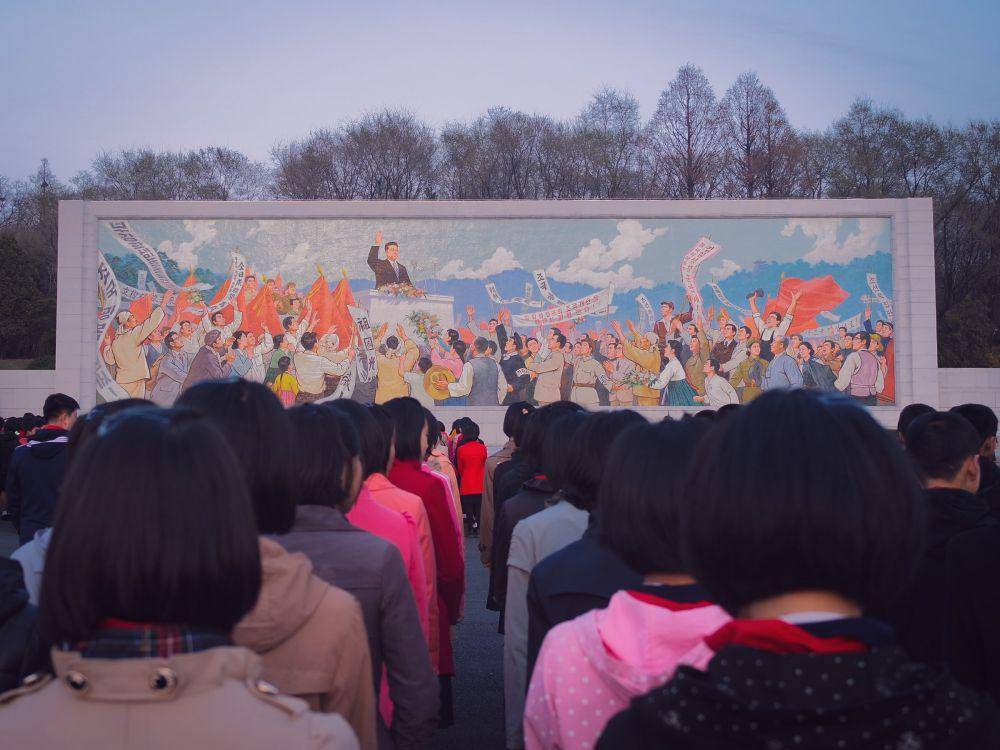 Anak-anak berbaris di depan mural di Pyongyang, Korea Utara. (unsplash.com/Thomas Evans)