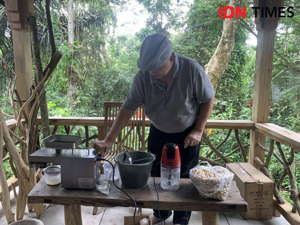 Anshori Djausal sedang mengepres biji kemiri menjadi minyak. (IDN Times/Rohmah Mustaurida).