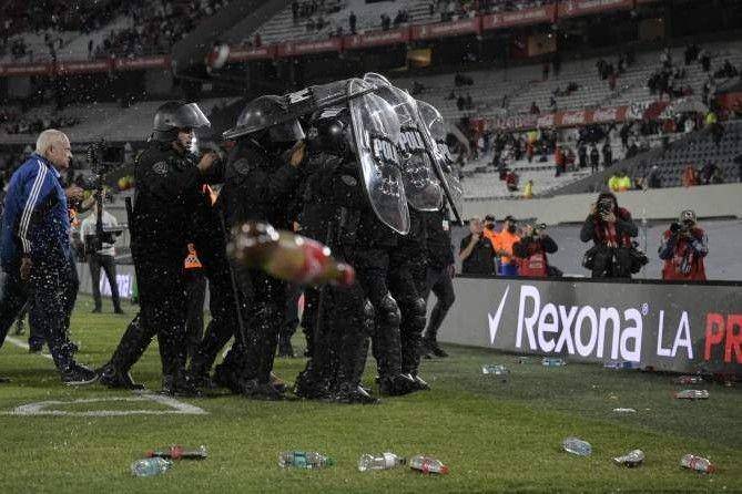 Para pemain Boca Junior dilindungi polisi dari lemparan suporter / The Sun
