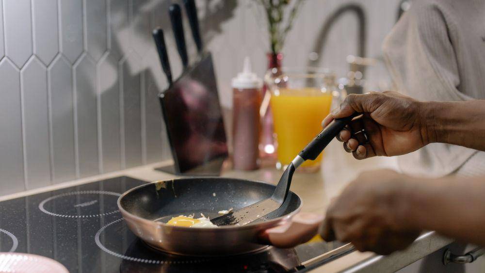ilustrasi orang memasak telur dengan menggunakan kompor induksi (pexels.com/cottonbro)