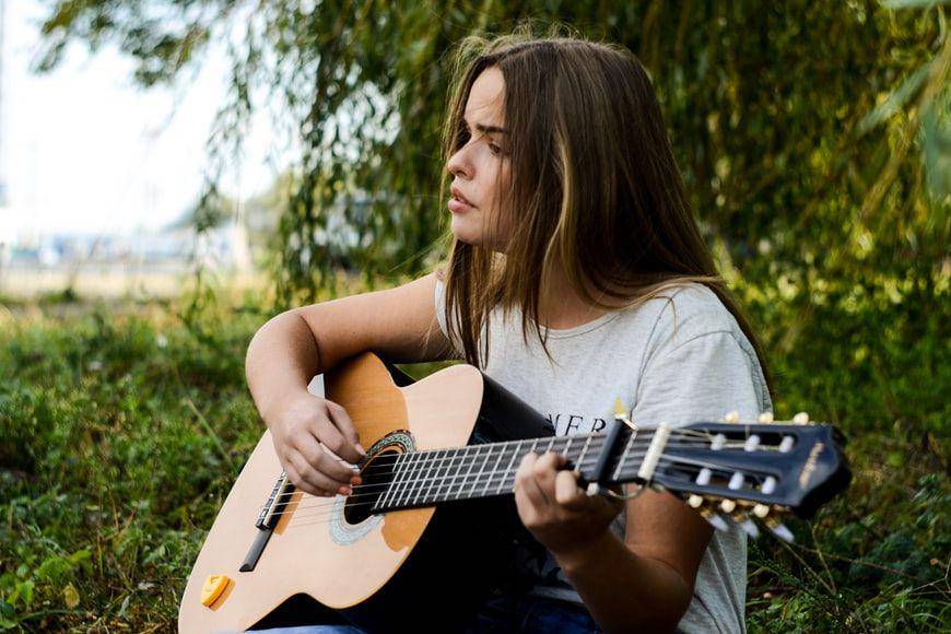 ilustrasi seorang wanita bermain gitar (Unsplash.com/ Mariana Vusiatytska)