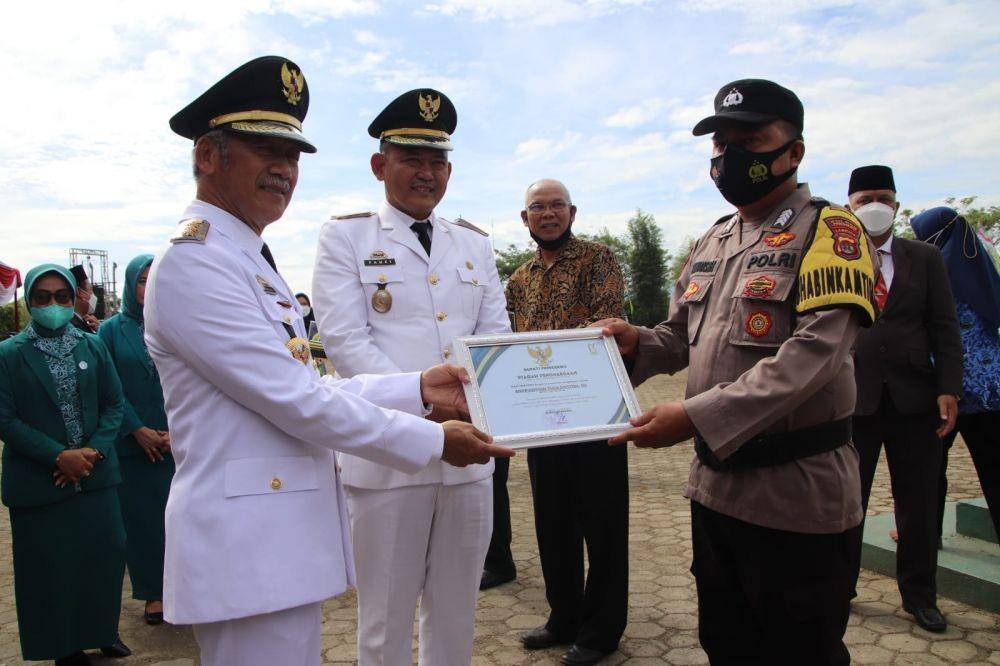 Bhabinkamtibmas Polsek Gadingrejo Bripka Andriansyah Yuga Saputra menerima penghargaan dari Bupati Pringsewu, Sujadi, Minggu (3/4/2022). (Dok. Polres Pringsewu).