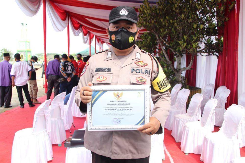 Bhabinkamtibmas Polsek Gadingrejo Bripka Andriansyah Yuga Saputra menerima penghargaan dari Bupati Pringsewu, Sujadi, Minggu (3/4/2022). (Dok. Polres Pringsewu).