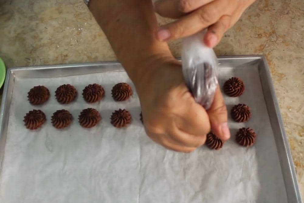 Ilustrasi mencetak kue semprit cokelat di atas loyang (youtube.com/FATMAH BAHALWAN)