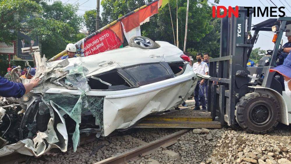 Minibus yang tertabrak KRL di evakuasi menggunakan forklift di palang pintu kereta manual Rawageni, Kecamatan Cipayung, Kota Depok. (IDNTimes/Dicky)