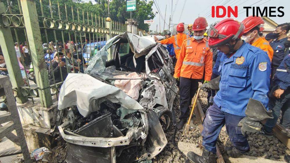 Petugas DPKP Kota Depok bersama PT KAI melakukan evakuasi minibus tertabrak KRL di Rawageni, Kecamatan Cipayung, Kota Depok. (IDNTimes/Dicky)