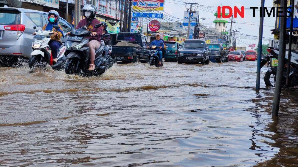 Sejumlah pengendara melintasi genangan air di Jalan Raya Sawangan, Kecamatan Pancoran Mas, Kota Depok. (IDNTimes/Dicky)