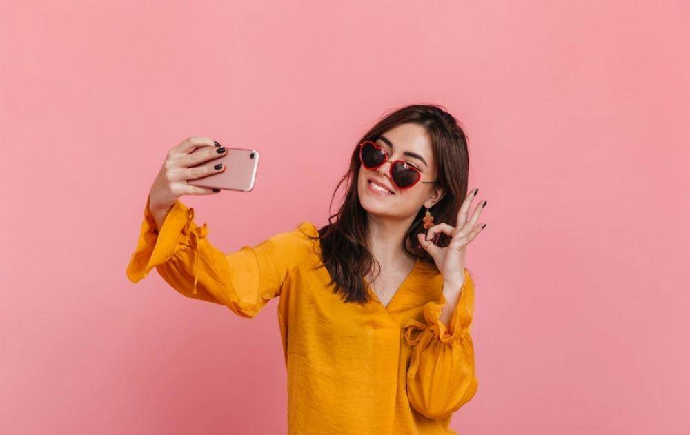 ilustrasi seorang perempuan sedang selfie (freepik.com/lookstudio)