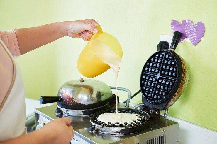 ilustrasi menuangkan adonan ke waffle maker (freepik.com/pressfoto)