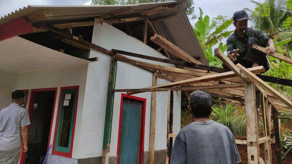 Para petugas dari Kementerian Sosial bergotong royong dengan berbagai unsur masyarakat setempat, memperbaiki rumah Mirah. (Dok. Kemensos)