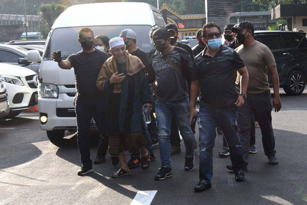 Sejumlah polisi mengamankan kedatangan petinggi organisasi Khilafatul Muslimin, Abdul Qadir Baraja (kedua kiri) saat tiba di Polda Metro Jaya, Jakarta, Selasa (7/6/2022). (ANTARA FOTO/Aditya Pradana Putra)