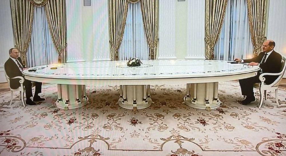 Presiden Rusia, Vladimir Putin (kiri) duduk di meja panjang 6 meter ketika menerima Kanselir Jerman pada 15 Februari 2022 di Moskow. (www.twitter.com/@Mike_Eckel)