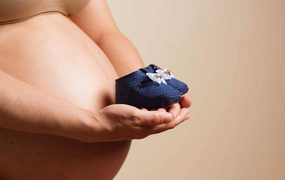 Ibu hamil memegang sepatu balita biru (pexels.com/Daniel Reche)