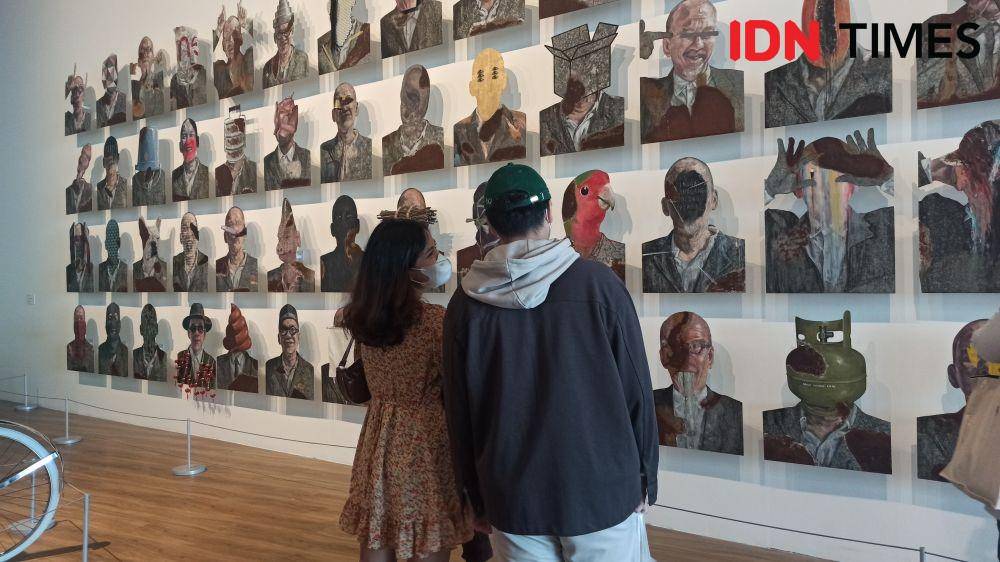 Pasangan pengunjung yang sedang menikmati salah satu karya Agus Suwage di Museum MACAN. (IDN Times/Kamila Sayara Avicena)