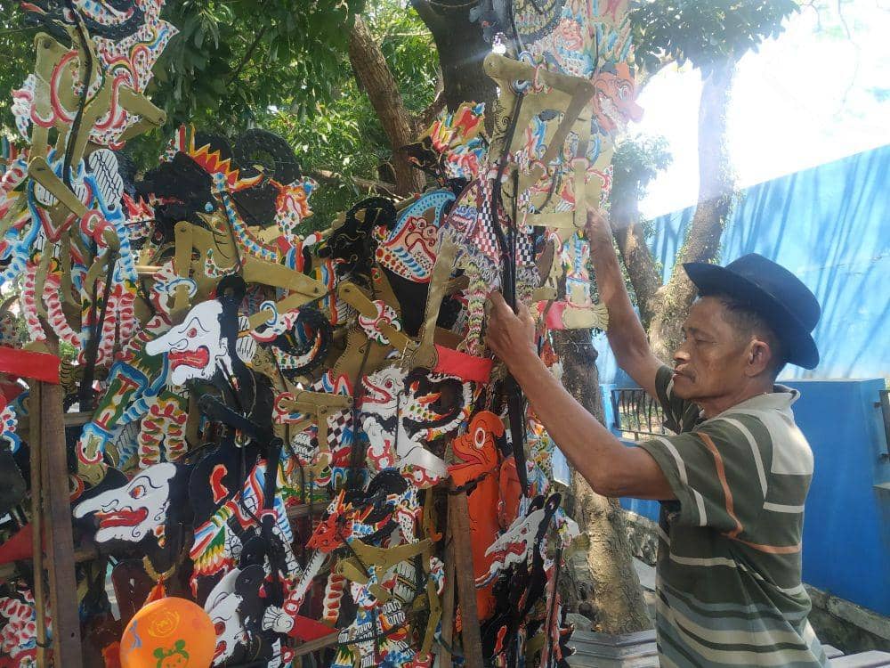 Sabar saat menata dagangannya sebelum melanjutkan perjalanan jualan wayang. IDN Times/Alfi Ramadana