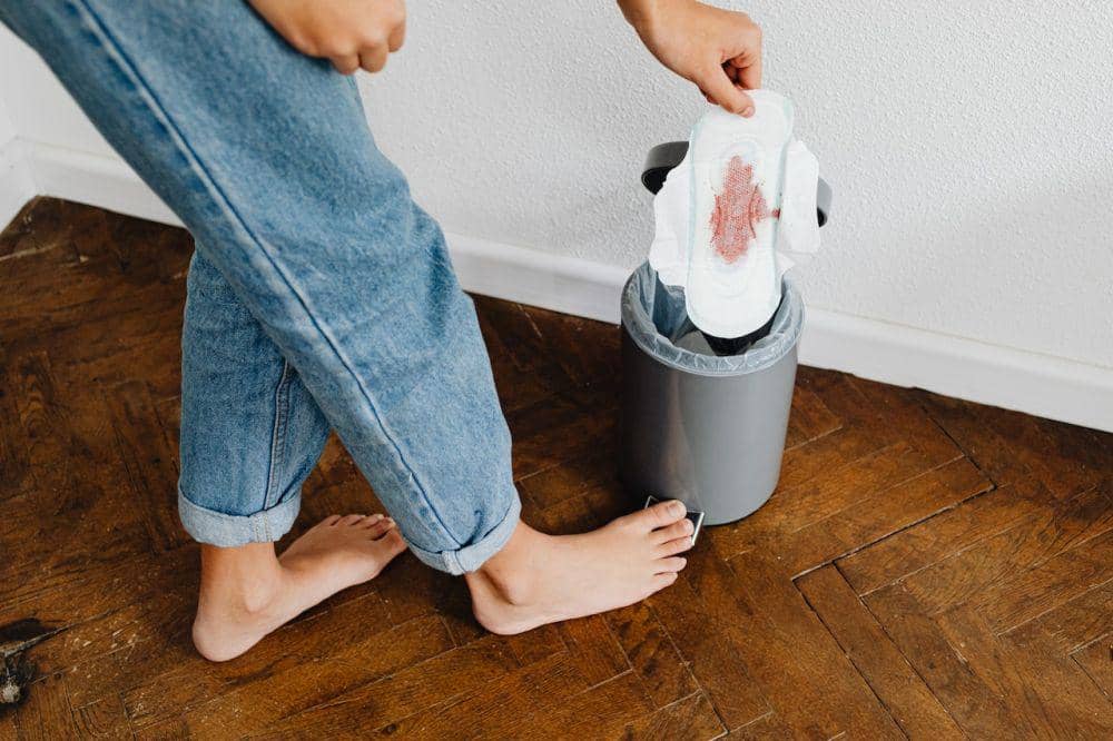 Seorang perempuan membuang pembalut sekali pakai ke tempat sampah.