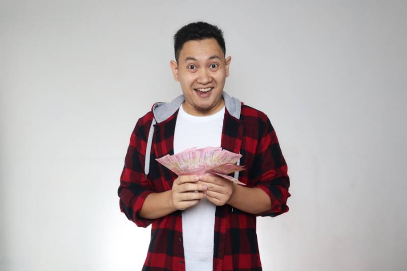 ilustrasi laki-laki memegang uang Rupiah (canva.com)