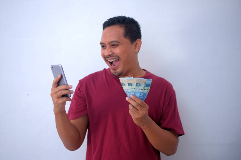 ilustrasi laki-laki memegang uang Rupiah (canva.com)