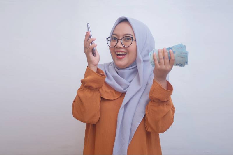 ilustrasi perempuan memegang uang Rupiah (canva.com)