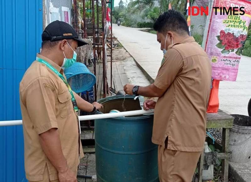 Dua orang petugas menaburkan bubuk abate ke air dalam drum milik warga Petung Penajam (IDN Times/Ervan)