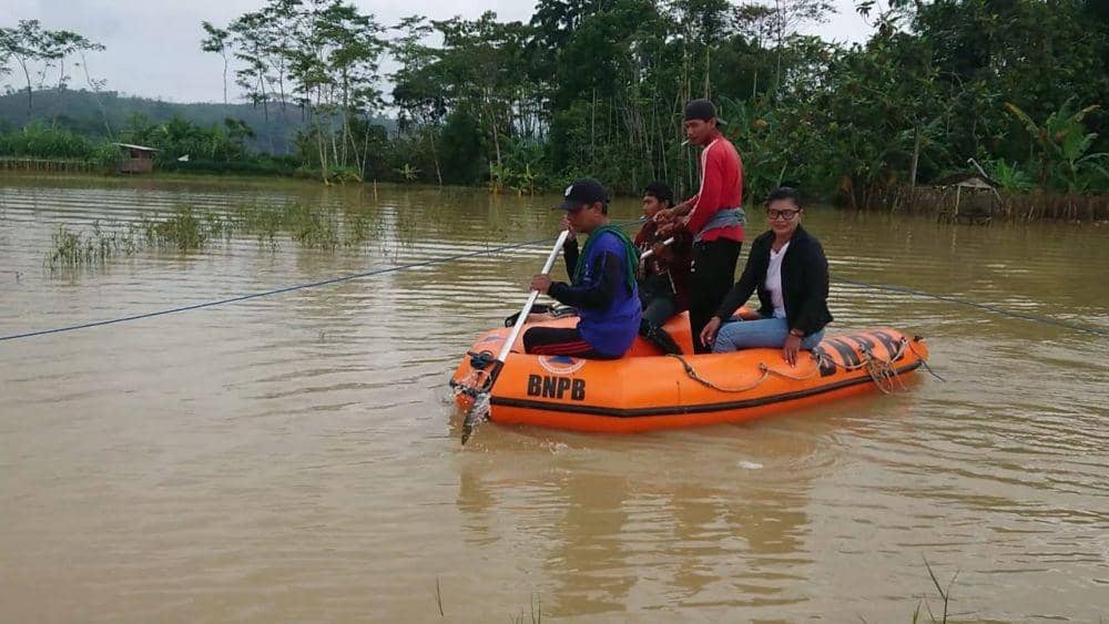 Warga menggunakan perahu karet untuk melintasi genangan banjir. IDN Times / Bramanta Pamungkas