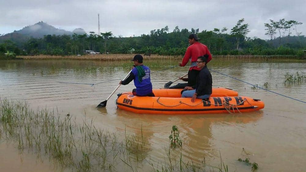 Warga menggunakan perahu karet untuk melintasi genangan banjir. IDN Times / Bramanta Pamungkas