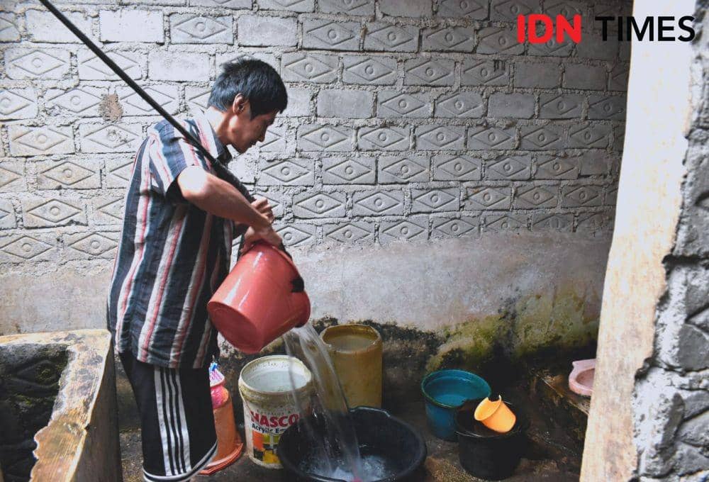 Pasien ODGJ Denni Sopian sedang melakukan pekerjaan rumah menimba air dari sumur. IDN Times/Debbie Sutrisno