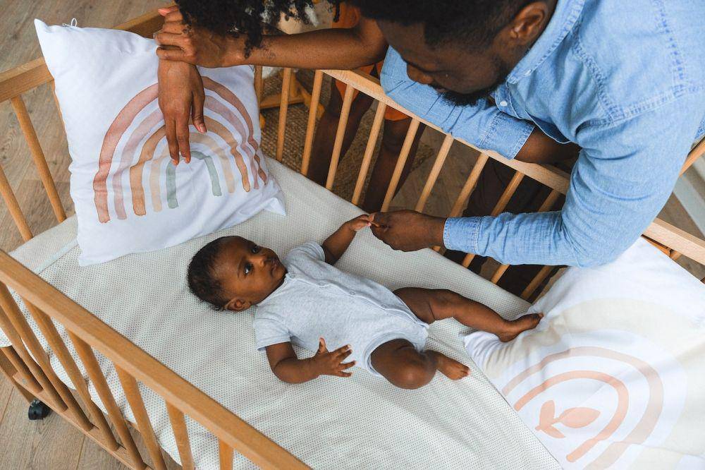 ilustrasi orangtua menidurkan anak di baby crib (pexels.com/Anna Shvets)