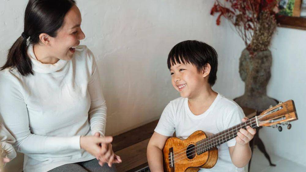 ilustrasi anak bermain ukulele di samping ibunya (pexels.com/Ketut Subiyanto)
