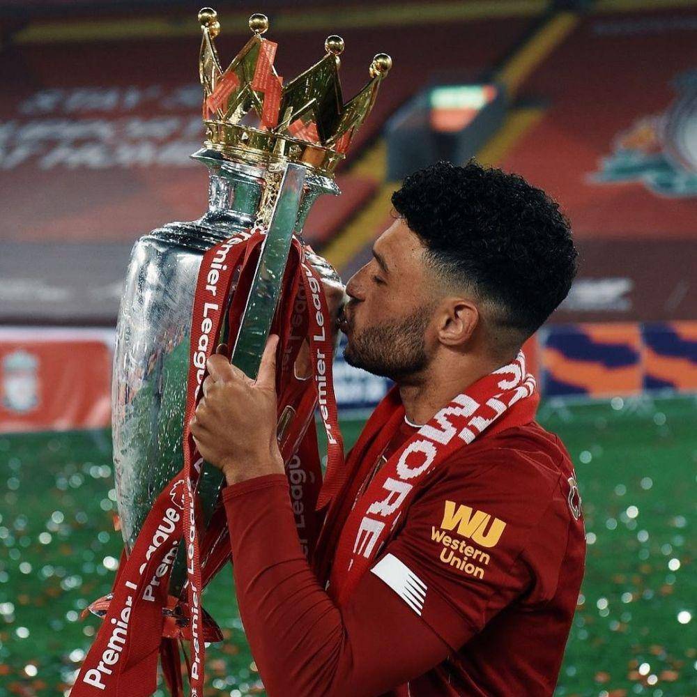 Alex Oxlade-Chamberlain mencium trofi EPL 2019/2020. (instagram.com/alexoxchamberlain)