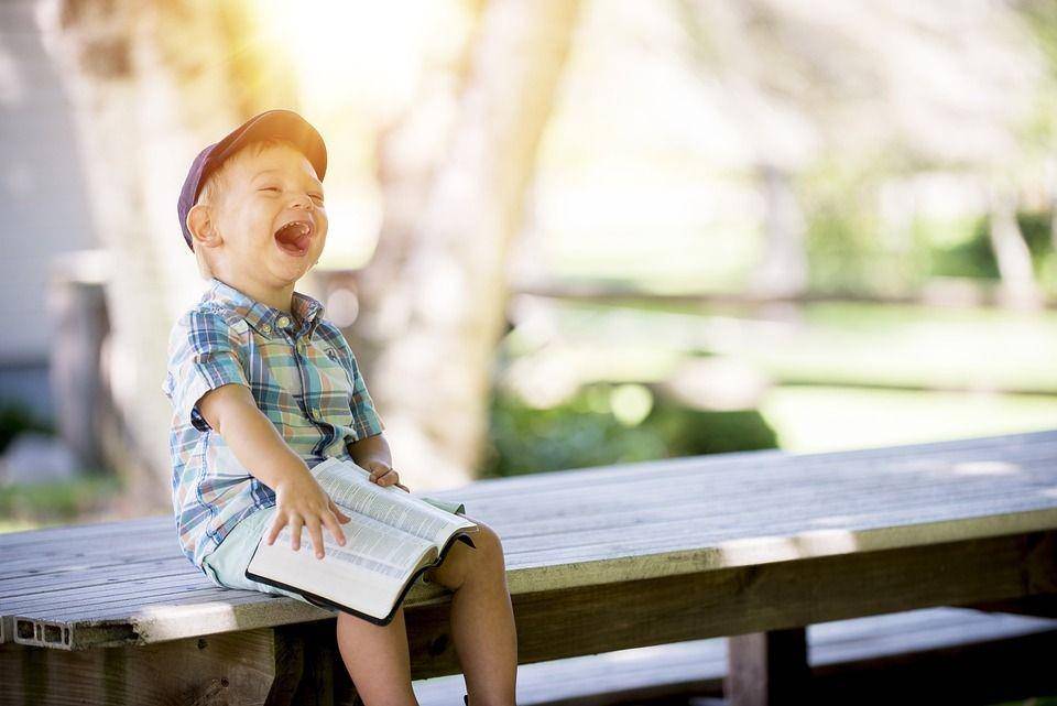 ilustrasi seorang anak yang sedang tertawa saat membaca (pixabay.com/StockSnap)