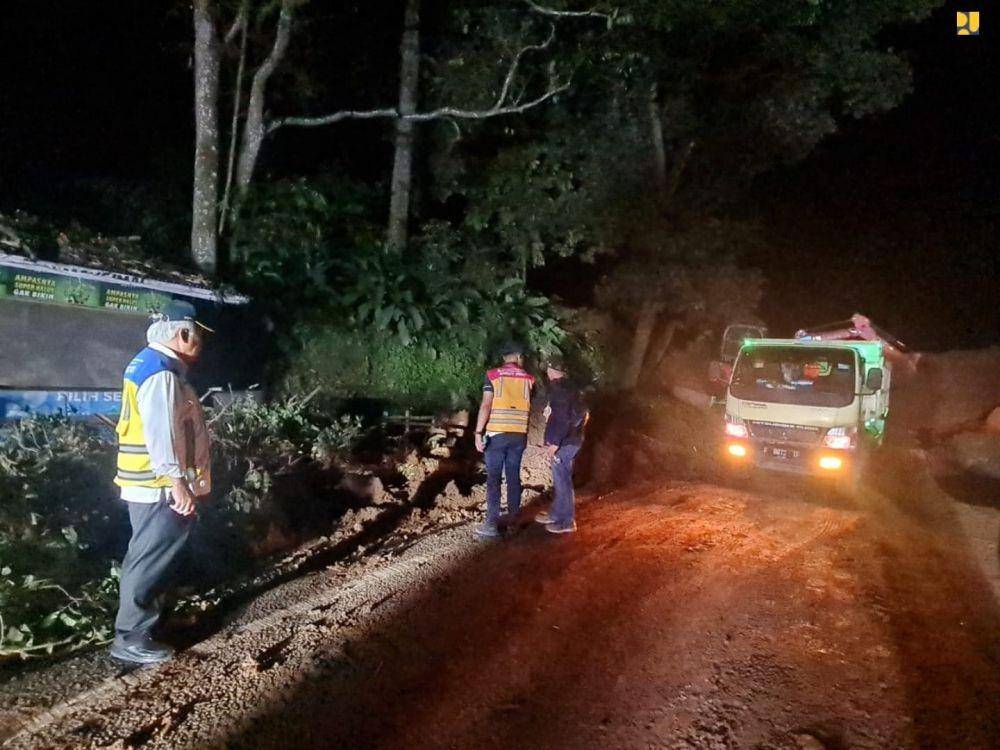 Excavator dan dump truck membersihkan pohon dan tanah longsoran yang menutup jalan. (dok. Kementerian PUPR)