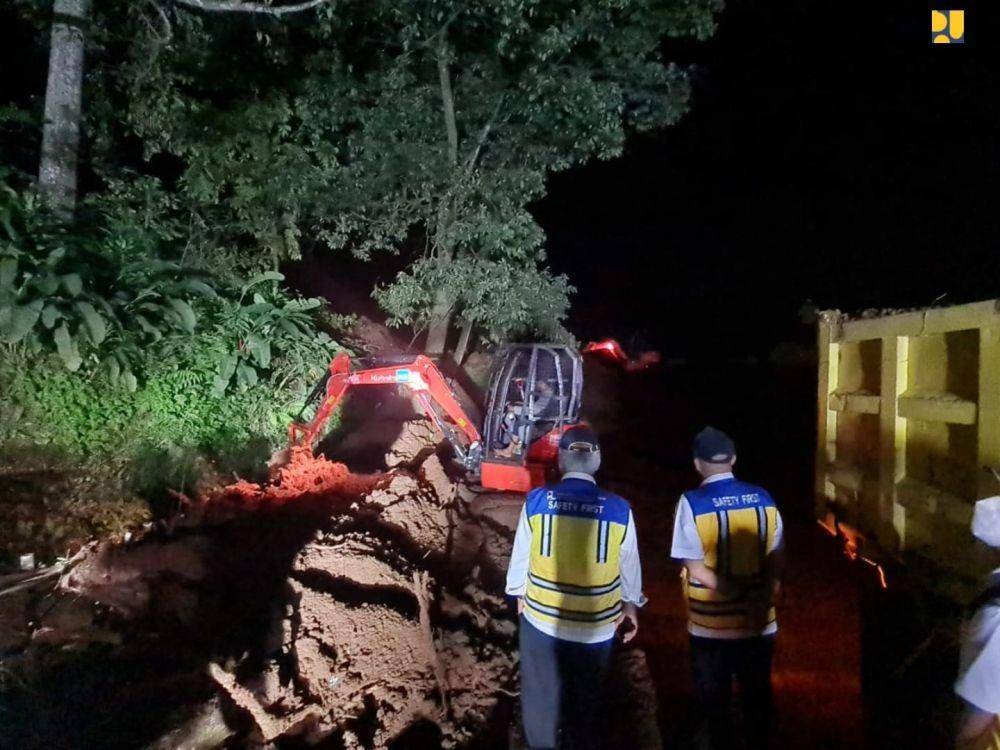 Excavator dan dump truck membersihkan pohon dan tanah longsoran yang menutup jalan. (dok. Kementerian PUPR)