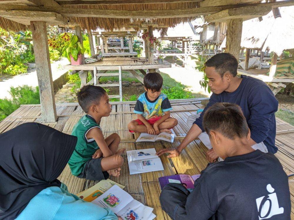 Ahmad, pegiat pendidikan di Kecamatan Wawo, Kab. Bima, Nusa Tenggara Barat, mengajak anak-anak membaca buku di Uma Lengge Mengajar. Dok. Kemendikbudristek