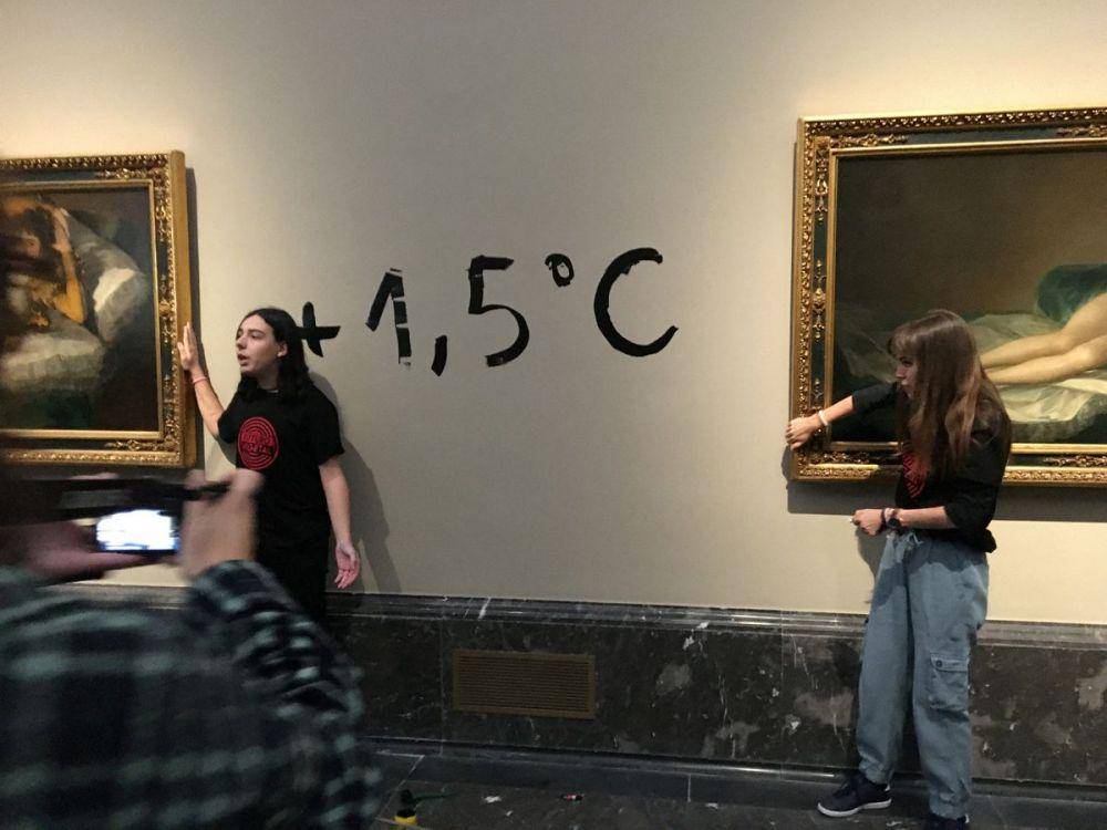 Aktivis menempelkan tangan pada bingkai The Clothed Maja dan The Naked Maja. (reuters.com)
