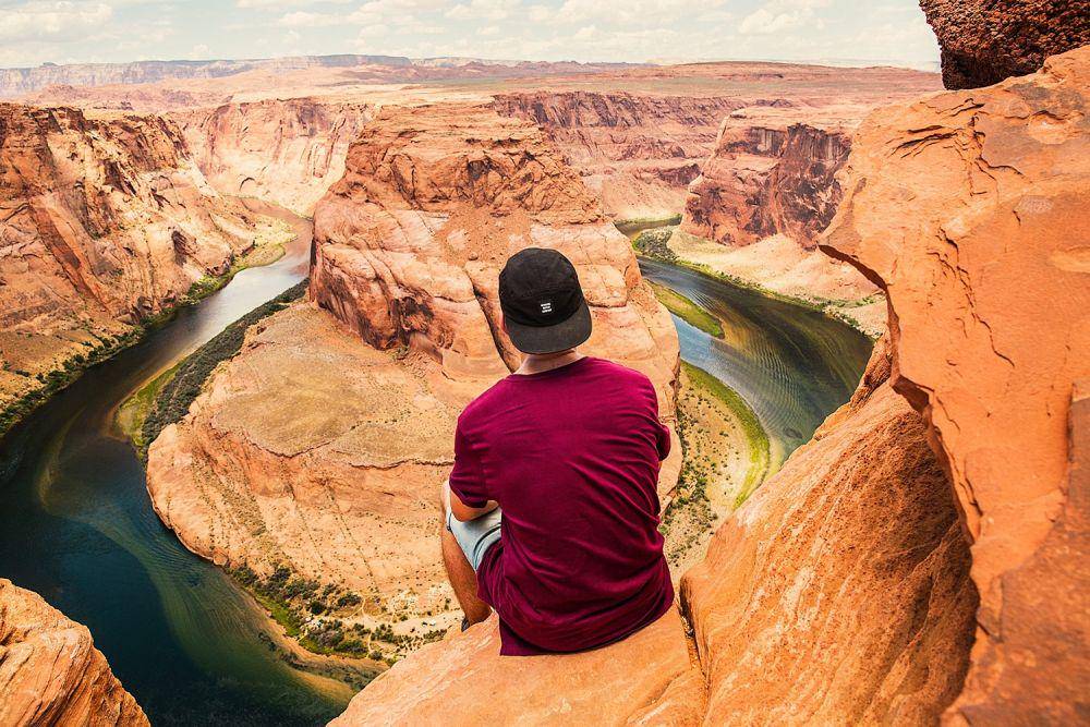 gambar pria sedang duduk dipinggir tebing (unsplash.com/Joshua Earle)