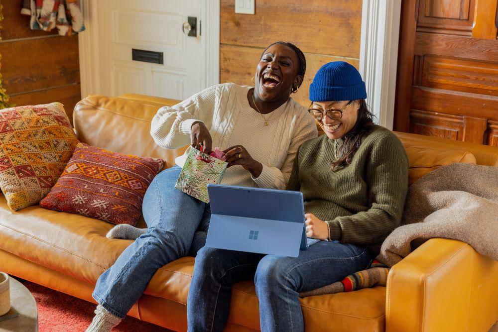 gambar dua orang sedang tertawa didepan laptop (unsplash.com/Surface)