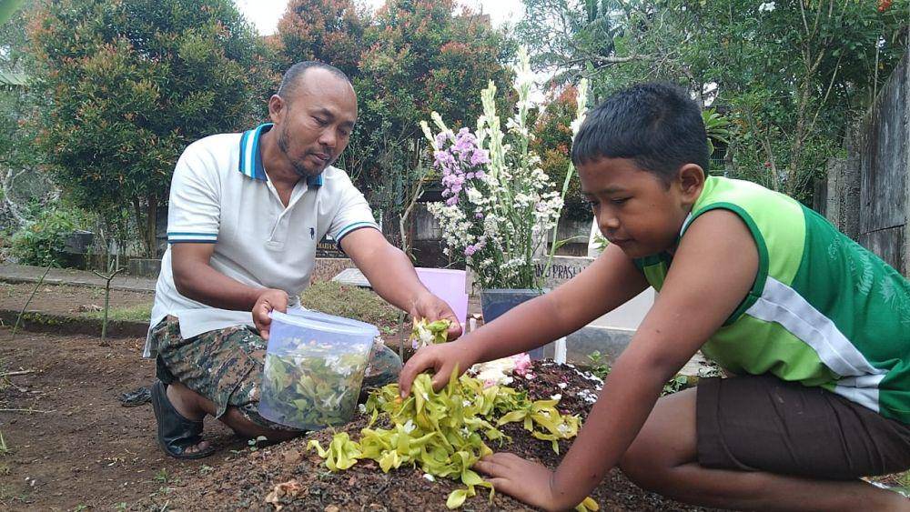 Vincensius dan adik laki-laki Revano saat mendatangi makam Revano. (IDN Times/Rizal Adhi Pratama)