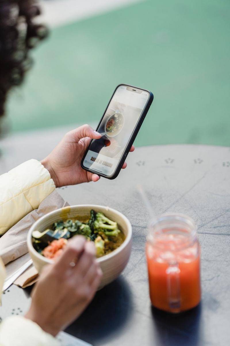 Seorang wanita sedang berselancar di dunia maya ketika sedang makan (Pexels.com/Blue Bird)