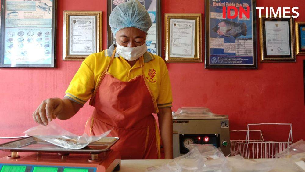 Seorang pekerja Kelompok Pengolah dan Pemasar Olahan Ikan (Poklahsar) UD Putri Laut Kemijen Semarang saat menimbang bobot ikan bandeng presto yang telah dikemas dan siap dipasarkan ke pelanggannya. Di (IDN Times/Fariz Fardianto)