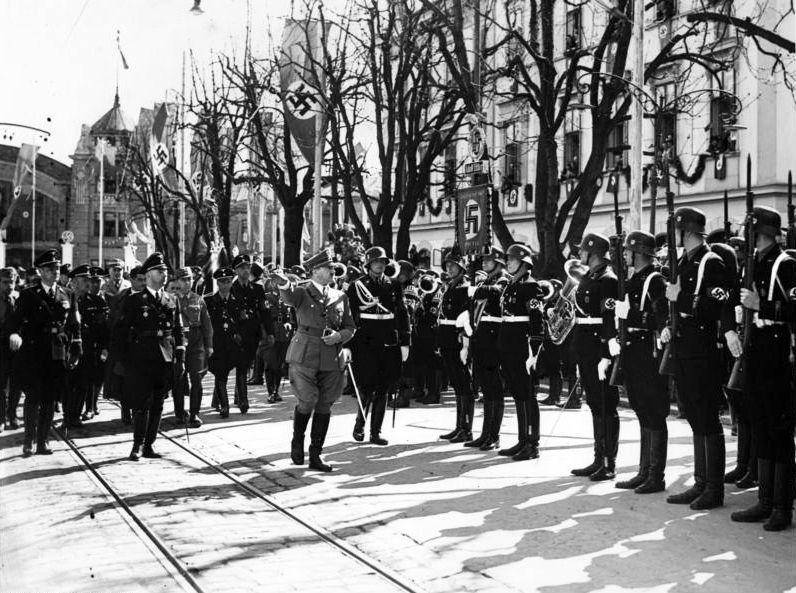 Adolf Hitler bersama Heinrich Himmler di depan Divisi 1 Schutzstaffel (SS) Panzer pada tahun 1938 di Klagenfurt. Schutzstaffel sendiri merupakan unit keamanan yang bertanggung jawab atas tindakan represif dan pembunuhan lawan politik Hitler beberapa tahun sebelumnya. (commons.wikimedia.org/German Federal Archives)