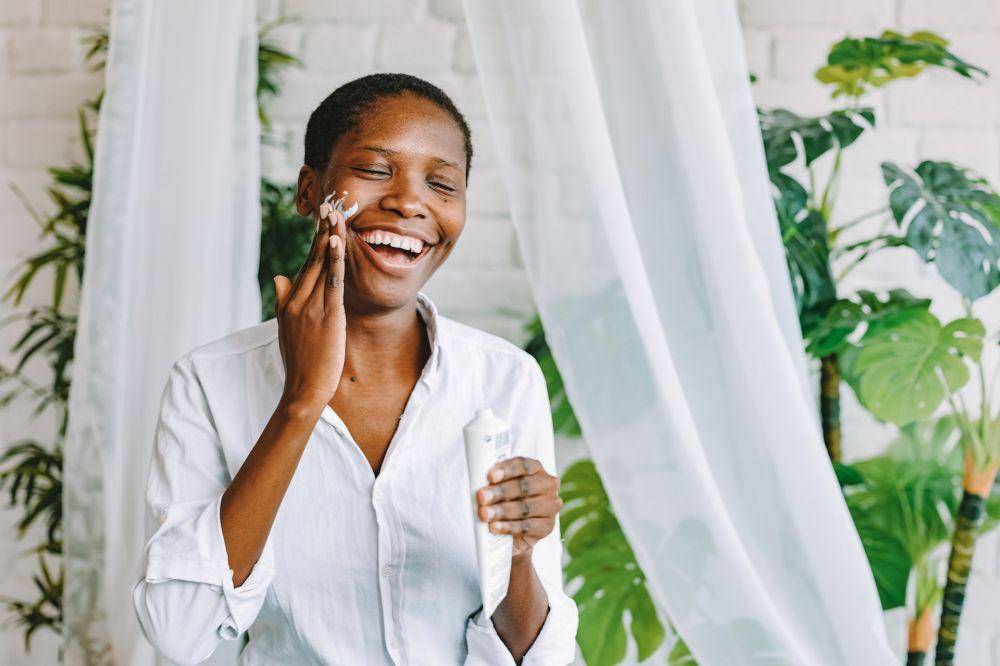 ilustrasi wanita berbaju putih mengaplikasikan hybrid sunscreen ke wajah (pexels.com/ROMAN ODINTSOV)