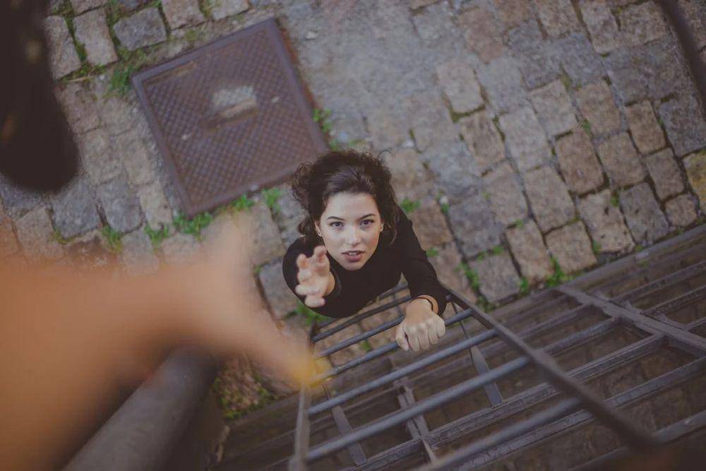Seorang wanita berusaha meraih tangan seseorang. (pexels.com/Samantha Garrote)