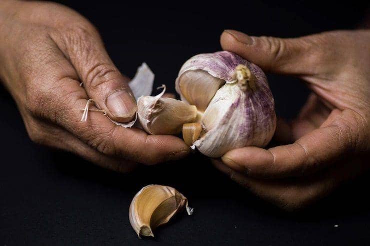 Seorang sedang mengupas bawang putih (freepik.com/wirestock)