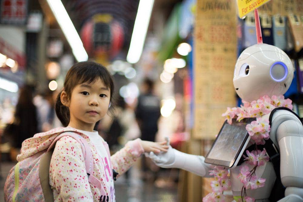 seorang anak yang bersalaman dengan robot (unsplash.com/Andy Kelly)