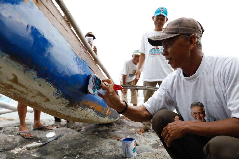 Relawan Komunitas Nelayan Pesisir memberikan bantuan berupa renovasi perahu dengan seperangkat kaleng cat dan kuas, Selasa (7/2/2023). (Dok. Komunitas Nelayan Pesisir)