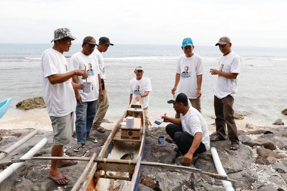 Relawan Komunitas Nelayan Pesisir memberikan bantuan berupa renovasi perahu dengan seperangkat kaleng cat dan kuas, Selasa (7/2/2023). (Dok. Komunitas Nelayan Pesisir)