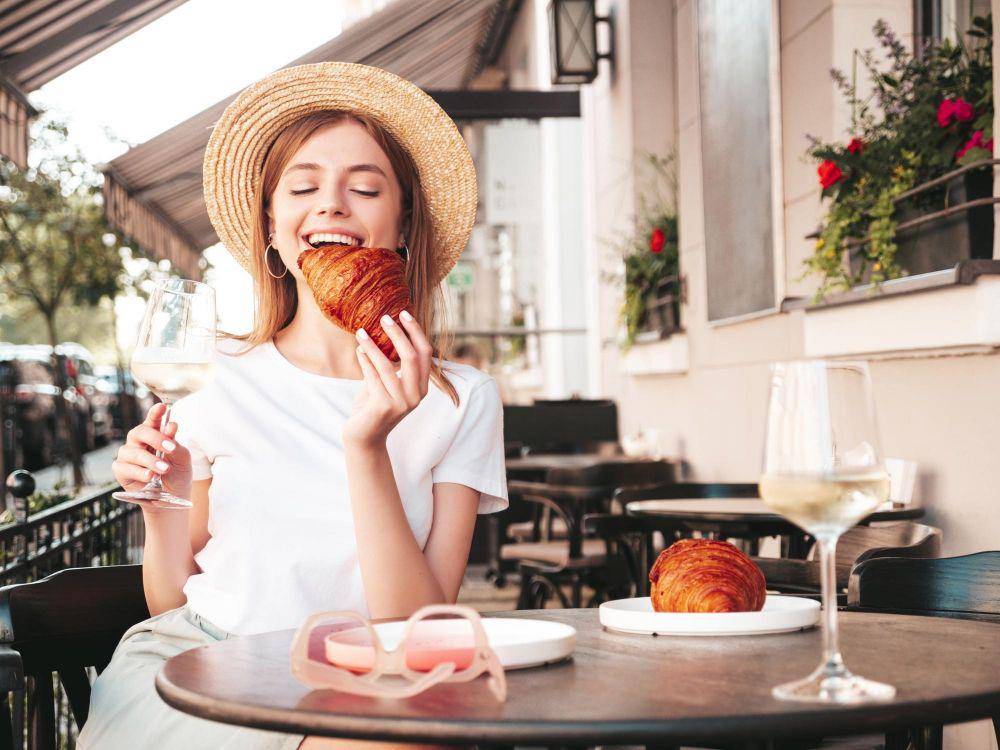 ilustrasi seorang wanita yang sedang menikmati croissant di Paris (freepik.com/halayalex)